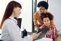 Female doctor pediatrician showing medical report or medical test results to young African mother and her tenn daughter