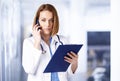 Female doctor portrait while talking with somebody on her mobile phone in the medical center Royalty Free Stock Photo