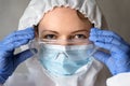 Female doctor in PPE suit close-up, nurse puts on medical glasses during COVID-19 pandemic