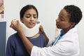 Female Doctor Putting Brace On Patient's Neck