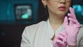 Female doctor putting on pink sterilized surgical gloves. Woman in doctor uniform wearing latex gloves before procedure