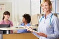 Female Doctor Reading Patient Notes At Nurses Station