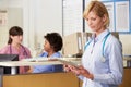 Female Doctor Reading Patient Notes At Nurses Station