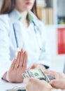 Female doctor refusing bribes or kickbacks, currencies dollar. Patient giving money for medical services. Concept of Royalty Free Stock Photo