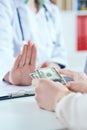 Female doctor refusing bribes or kickbacks, currencies dollar. Patient giving money for medical services. Concept of Royalty Free Stock Photo