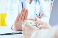 Female doctor refusing bribes or kickbacks, currencies dollar. Patient giving money for medical services. Concept of Royalty Free Stock Photo