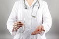 Female doctor's hand holding glass of water, giving pills. Close