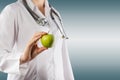 Female doctor's hand holding green apple. Close up shot on grey Royalty Free Stock Photo