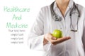 Female doctor's hand holding green apple. Close up shot on grey Royalty Free Stock Photo