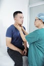 Doctor palpating neck of man