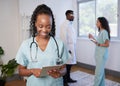 Female doctor in scrubs uses digital tablet with medical team in background Royalty Free Stock Photo