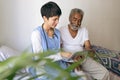 Female doctor and senior male patient using digital tablet at retirement home Royalty Free Stock Photo