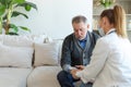 Female doctor senior man taking his blood pressure in doctor office or at home. Old man patient and doctor have Royalty Free Stock Photo