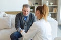 Female doctor senior man taking his blood pressure in doctor office or at home. Old man patient and doctor have Royalty Free Stock Photo