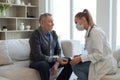 Female doctor senior man taking his blood pressure in doctor office or at home. Old man patient and doctor have Royalty Free Stock Photo