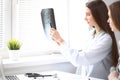 Female doctor showing x-ray to her patient while sitting at the table near the window in hospital. Physician is ready to Royalty Free Stock Photo