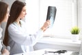 Female doctor showing x-ray to her patient while sitting at the table near the window in hospital. Physician is ready to Royalty Free Stock Photo