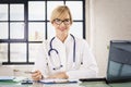 Female doctor sitting at desk in the doctor`s office and working Royalty Free Stock Photo