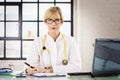 Female doctor sitting at desk in the doctor`s office and working Royalty Free Stock Photo