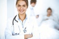 Female doctor smiling on the background with patient in the bed and two doctors Royalty Free Stock Photo