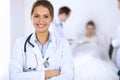 Female doctor smiling on the background with patient in the bed and two doctors Royalty Free Stock Photo