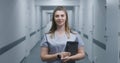 Female doctor stands in modern clinic corridor, looks at camera Royalty Free Stock Photo