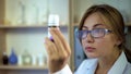 Female doctor studying medicine ingredients, staring at label of pill container