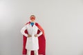 Female doctor in superhero costume on grey background. Superwoman in red cape and mask safeguarding public health Royalty Free Stock Photo