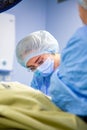 Female Doctor in Surgery Operating Hospital Room. Surgeon medic in protective work wear gloves, mask and cap