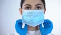Female doctor in surgical face mask close-up, professional medical care, trust