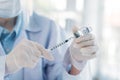 Female doctor with surgical face mask and face shield holding syringe with needle and COVID-19 Coronavirus vaccine tube