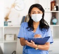 Female doctor in surgical mask filling out medical form