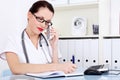 Female doctor talking by the phone and writing. Royalty Free Stock Photo