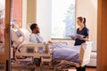 Female Doctor Talking To Male Patient In Hospital Bed