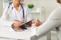 Female doctor therapist gross allergist nutritionist otolaryngologist and male patient sitting at a table in a clinic