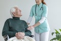 Female doctor touching an arm of her patient in a wheelchair