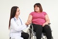 Female doctor treating an obese woman sitting in a wheelchair. Royalty Free Stock Photo