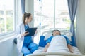 Female doctor treating young male patient in bed and talking with Asian male patient beside bed Royalty Free Stock Photo