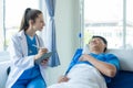 Female doctor treating young male patient in bed and talking with Asian male patient beside bed Royalty Free Stock Photo