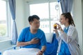 Female doctor treating young male patient in bed and talking with Asian male patient beside bed Royalty Free Stock Photo