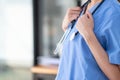 Female doctor in uniform holding a stethoscope waiting to examine a patient. A female doctor holds a stethoscope to prepare for