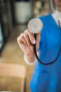 Female doctor in uniform holding a stethoscope waiting to examine a patient. A female doctor holds a stethoscope to prepare for