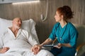 Female doctor holding hand of elderly male patient on bed at the hospital Royalty Free Stock Photo