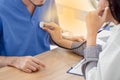 A Female doctor uses a stethoscope on a male patient