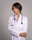 Female doctor wearing lab coat and stethoscope around her neck and standing at isolated background Royalty Free Stock Photo