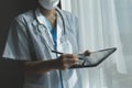 Female Doctor Wearing Scrubs In Hospital Corridor Using Digital Tablet Royalty Free Stock Photo