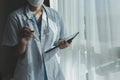 Female Doctor Wearing Scrubs In Hospital Corridor Using Digital Tablet Royalty Free Stock Photo