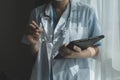 Female Doctor Wearing Scrubs In Hospital Corridor Using Digital Tablet Royalty Free Stock Photo