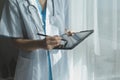 Female Doctor Wearing Scrubs In Hospital Corridor Using Digital Tablet Royalty Free Stock Photo