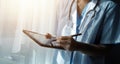 Female Doctor Wearing Scrubs In Hospital Corridor Using Digital Tablet Royalty Free Stock Photo